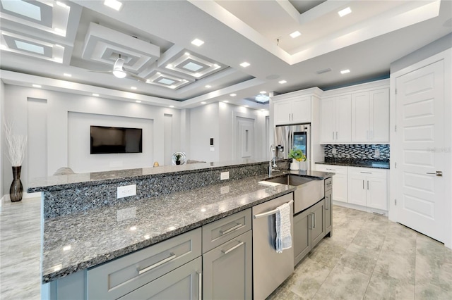 kitchen with gray cabinetry, stainless steel appliances, a sink, white cabinets, and a large island