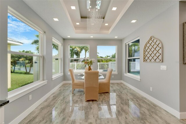 sunroom featuring a raised ceiling and a notable chandelier