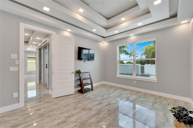 empty room with marble finish floor, baseboards, and a tray ceiling