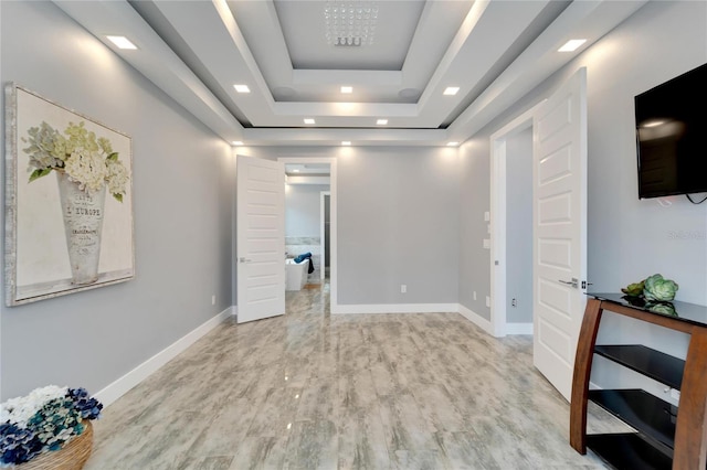 interior space with light wood finished floors, a raised ceiling, and baseboards