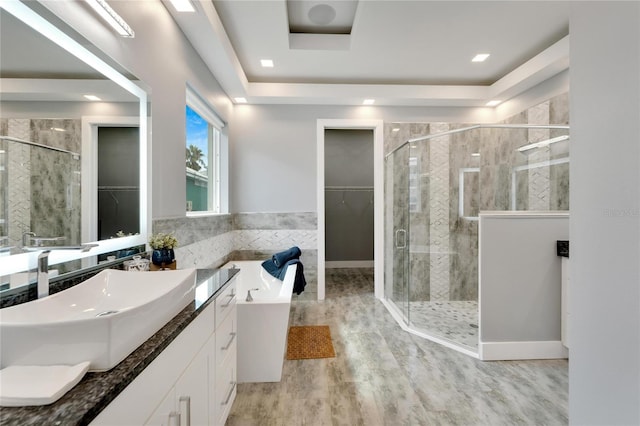 bathroom featuring a walk in closet, vanity, a shower stall, wood finished floors, and a bath