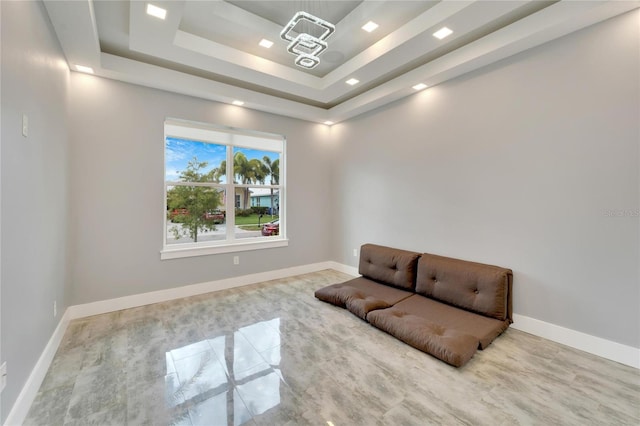 sitting room with a raised ceiling and baseboards