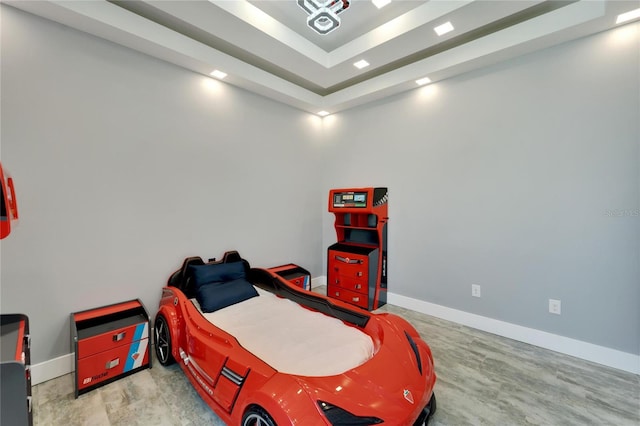 bedroom featuring a tray ceiling, baseboards, and wood finished floors