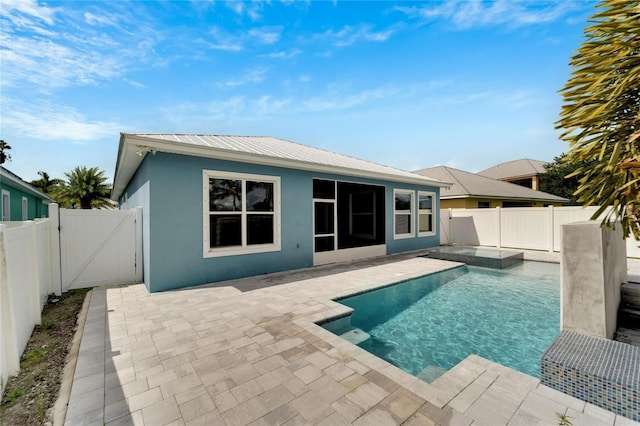 back of house featuring a fenced backyard, metal roof, a fenced in pool, and stucco siding