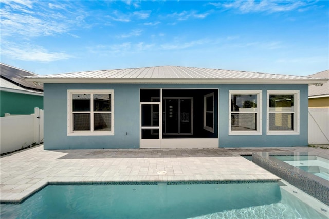 back of property featuring an in ground hot tub, stucco siding, fence, and an outdoor pool