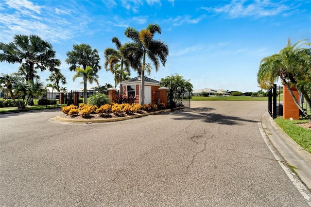 view of street featuring a gate, a gated entry, and curbs