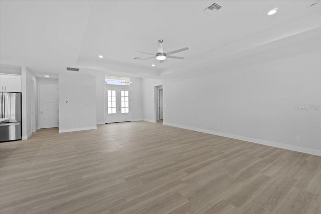 unfurnished living room with french doors, a raised ceiling, visible vents, and light wood-style floors