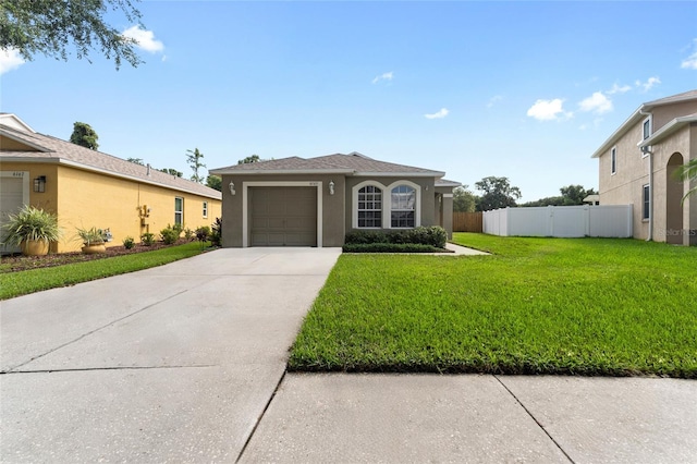 view of front of property with driveway, an attached garage, fence, a front yard, and stucco siding