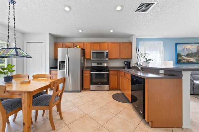 kitchen featuring visible vents, dark countertops, appliances with stainless steel finishes, pendant lighting, and a sink