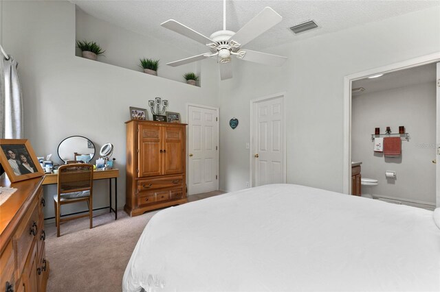 bedroom featuring a textured ceiling, ceiling fan, ensuite bathroom, and light carpet