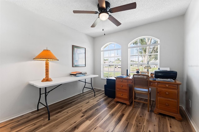 home office featuring a textured ceiling, dark wood-type flooring, a ceiling fan, and baseboards