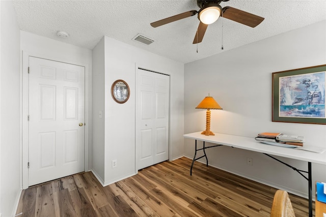 office area featuring baseboards, visible vents, a ceiling fan, dark wood-style flooring, and a textured ceiling