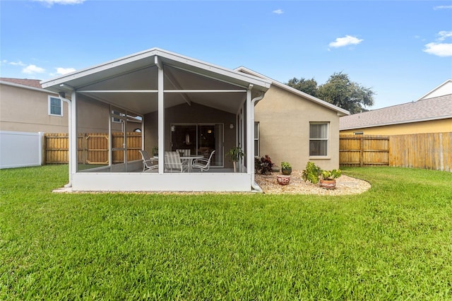 back of property with stucco siding, a fenced backyard, a sunroom, and a yard