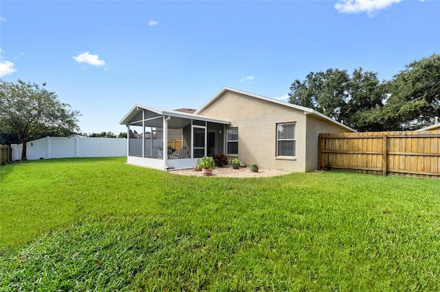 rear view of house with a sunroom, a fenced backyard, stucco siding, and a yard