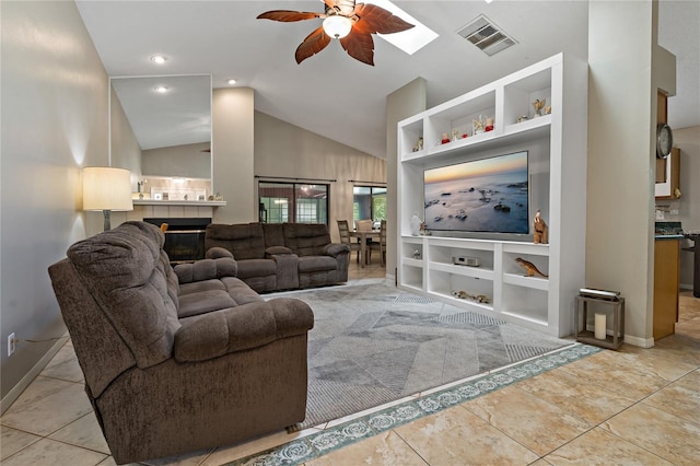 tiled living room with ceiling fan, a fireplace, and vaulted ceiling