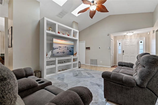 living room with built in features, ceiling fan, light tile patterned floors, and lofted ceiling with skylight