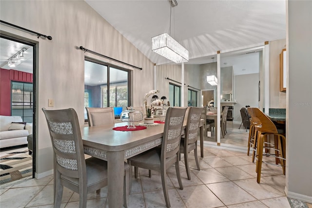 tiled dining room featuring an inviting chandelier and vaulted ceiling