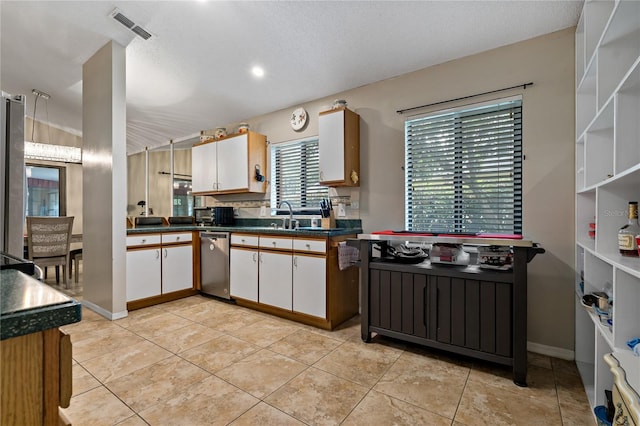 kitchen with sink, light tile patterned flooring, stainless steel dishwasher, and white cabinets