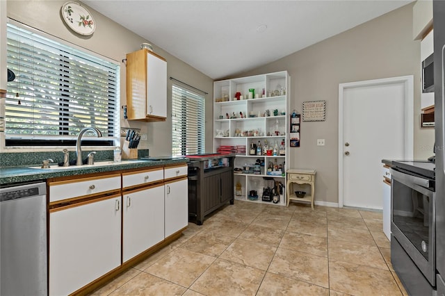 kitchen featuring appliances with stainless steel finishes, white cabinetry, sink, lofted ceiling, and light tile patterned flooring