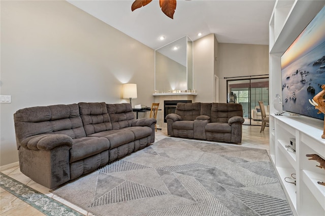 tiled living room featuring ceiling fan, a fireplace, and a towering ceiling