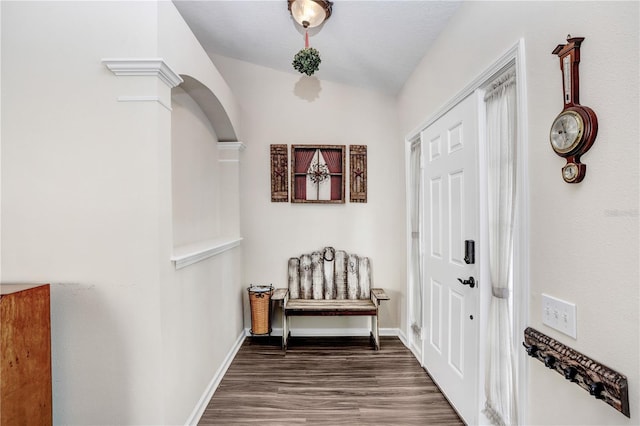 foyer entrance with dark wood-type flooring, lofted ceiling, and ornate columns