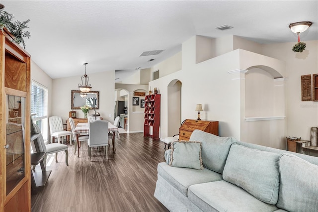 living room featuring lofted ceiling, dark hardwood / wood-style floors, and decorative columns