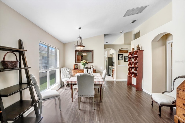 dining space with dark wood-type flooring and vaulted ceiling