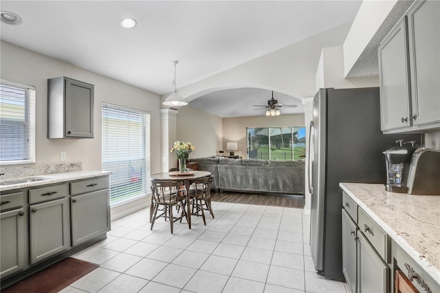 kitchen with light wood-type flooring, gray cabinets, stainless steel fridge, decorative light fixtures, and ceiling fan