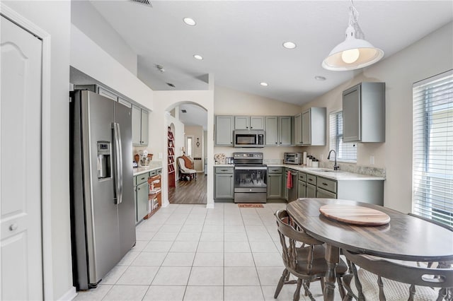 kitchen with pendant lighting, light hardwood / wood-style flooring, stainless steel appliances, sink, and vaulted ceiling