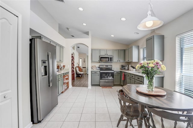 kitchen with vaulted ceiling, gray cabinetry, pendant lighting, light hardwood / wood-style flooring, and stainless steel appliances