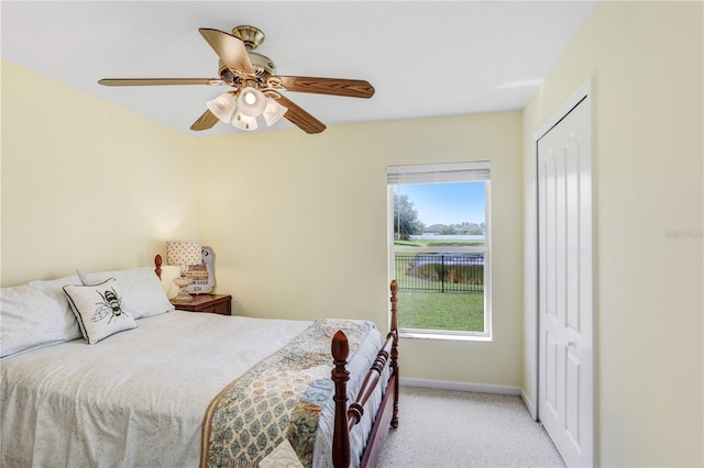 carpeted bedroom with ceiling fan, a closet, and multiple windows