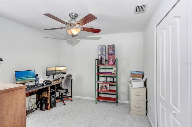 carpeted home office with ceiling fan and a textured ceiling