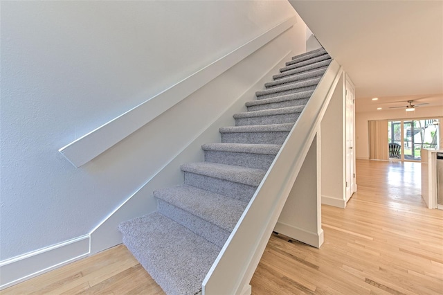 stairway with hardwood / wood-style floors and ceiling fan