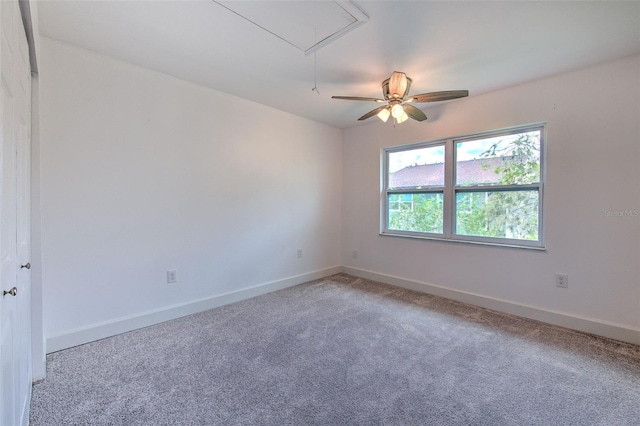 unfurnished room with attic access, carpet flooring, and baseboards