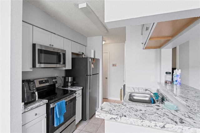 kitchen featuring light countertops, appliances with stainless steel finishes, a sink, and white cabinetry