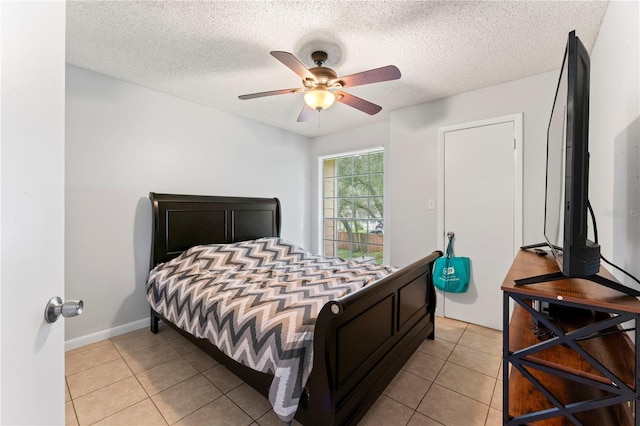 bedroom featuring light tile patterned floors, ceiling fan, baseboards, and a textured ceiling