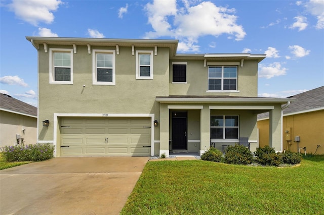 view of front facade with stucco siding, a garage, concrete driveway, and a front yard