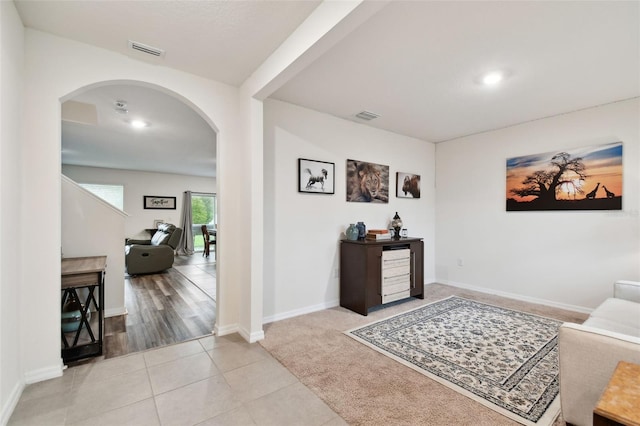 interior space with light tile patterned floors, arched walkways, visible vents, and baseboards