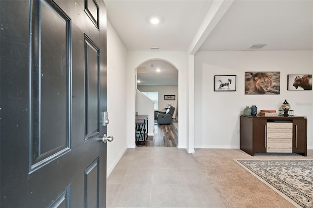 foyer entrance with visible vents, arched walkways, baseboards, and light tile patterned flooring