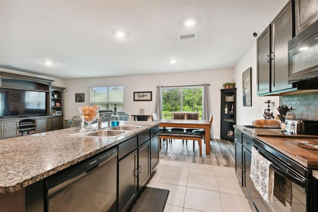 kitchen with appliances with stainless steel finishes, light hardwood / wood-style floors, tasteful backsplash, sink, and a kitchen island with sink