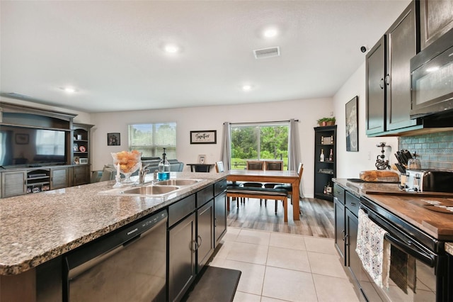 kitchen with a wealth of natural light, visible vents, black appliances, a sink, and tasteful backsplash