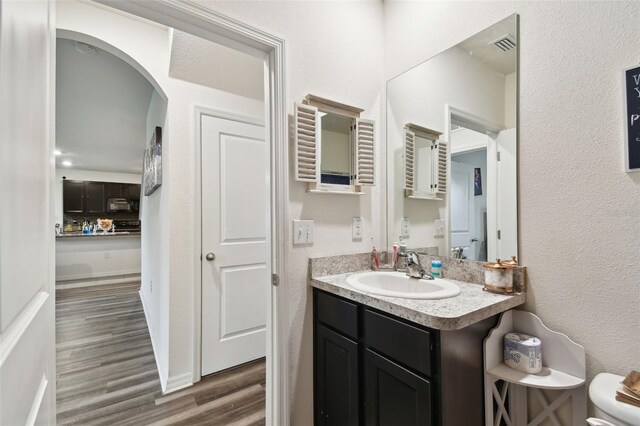 bathroom with toilet, hardwood / wood-style flooring, and vanity