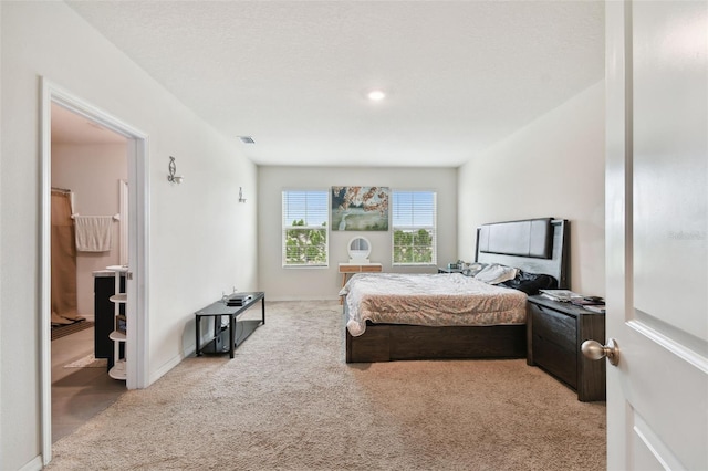 bedroom with visible vents, light carpet, baseboards, and connected bathroom