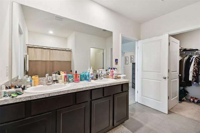 bathroom with a sink, a walk in closet, a shower with curtain, and double vanity