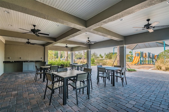 view of patio with ceiling fan, sink, a playground, and exterior kitchen