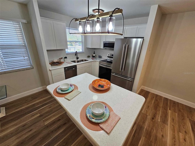 kitchen with stainless steel appliances, sink, hanging light fixtures, dark wood-type flooring, and white cabinets