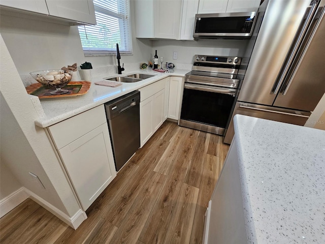 kitchen with white cabinetry, wood-type flooring, stainless steel appliances, and sink