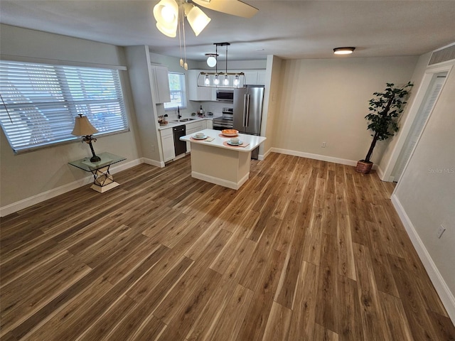 kitchen featuring stainless steel appliances, a kitchen island, sink, dark hardwood / wood-style floors, and white cabinets