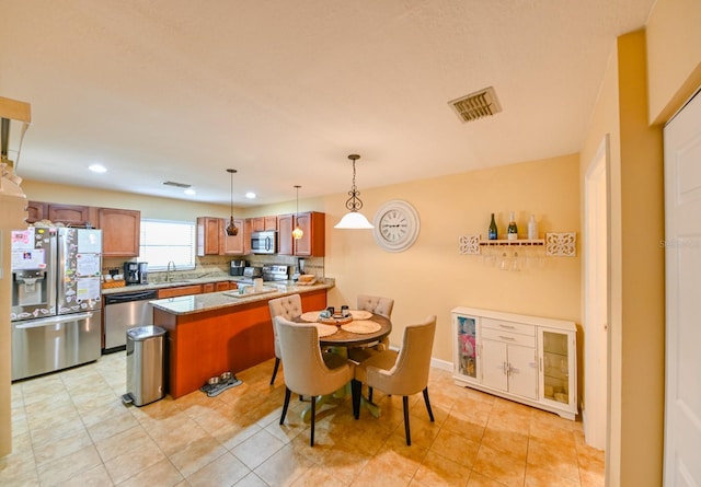 kitchen with kitchen peninsula, a kitchen breakfast bar, stainless steel appliances, sink, and hanging light fixtures