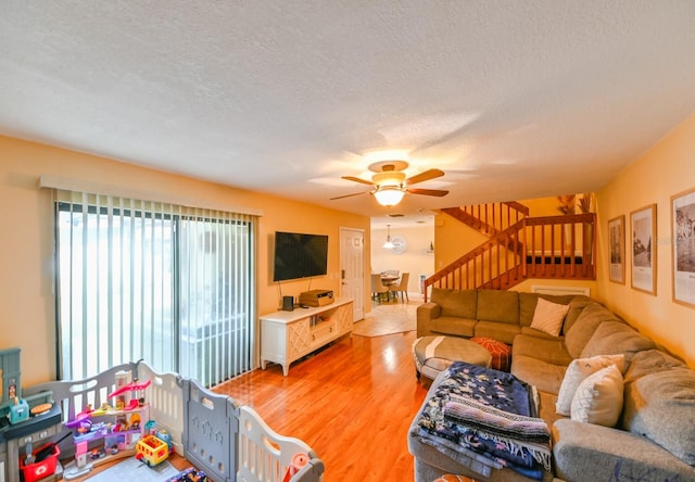 living room featuring ceiling fan, wood-type flooring, and a textured ceiling